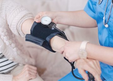 Close up of female doctor checking pressure of elderly patient